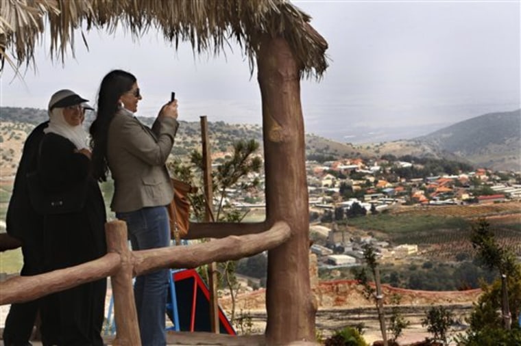 A Lebanese woman takes pictures with her mobile phone of an Israeli settlement which is seen in the bacground, at a newly opened border park, at the Lebanese border village of Maroun el-Rass on the Lebanon-Israel border.